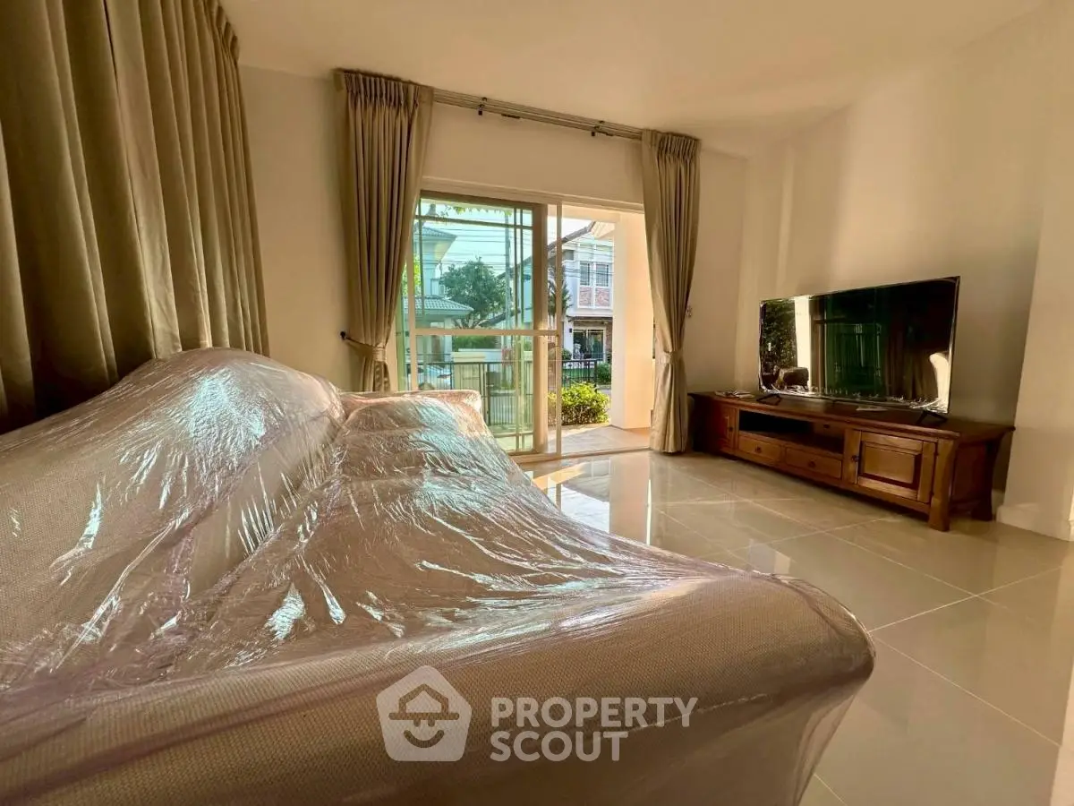 Spacious living room with large windows and modern furnishings, offering a bright and inviting atmosphere.