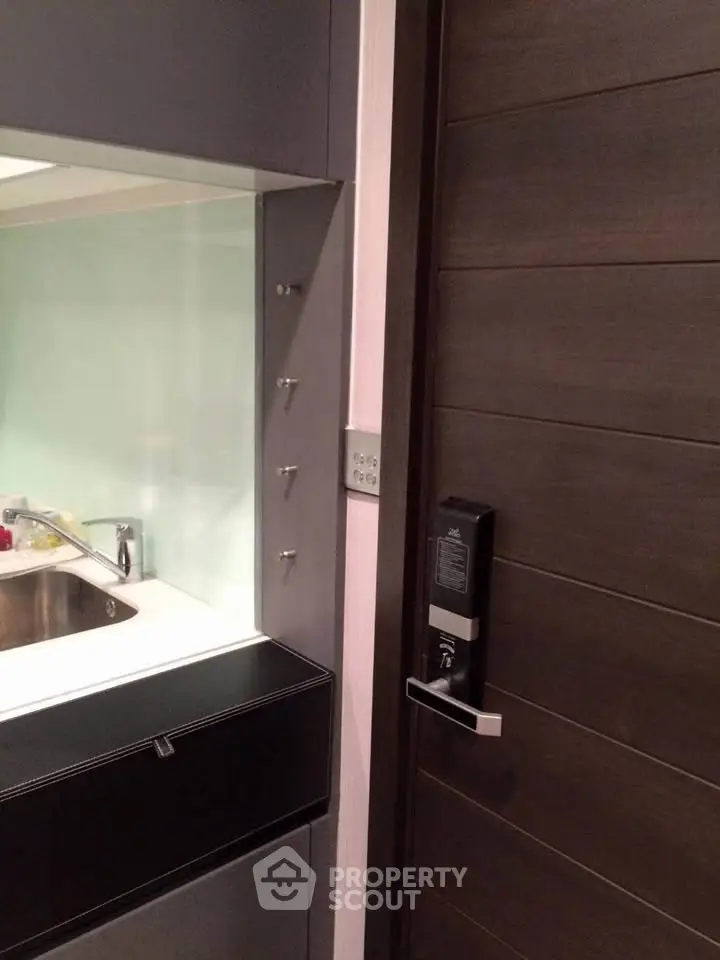 Modern kitchen with sleek cabinetry and electronic door lock for enhanced security.