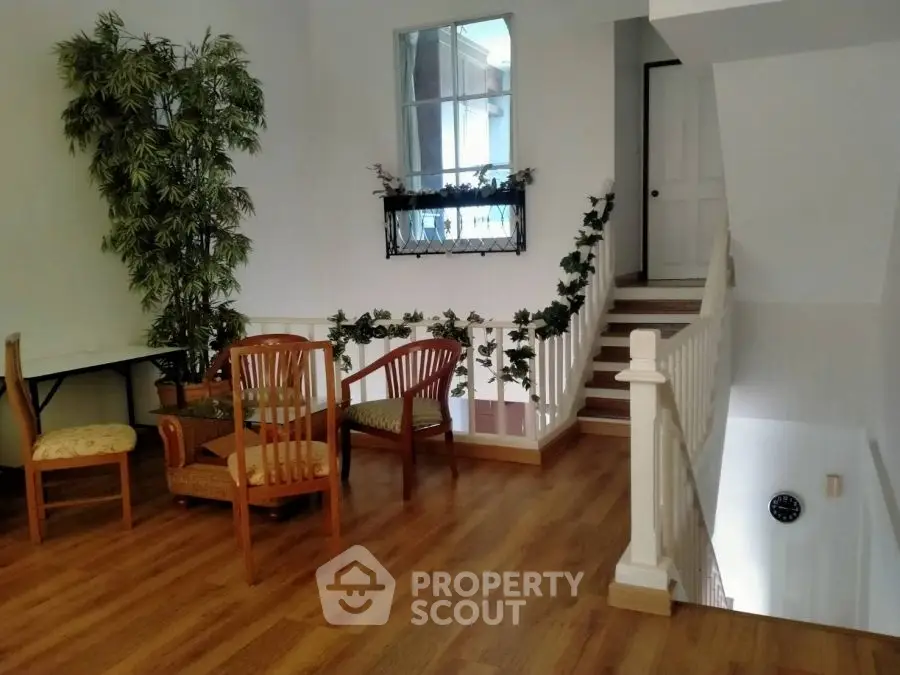 Charming interior with wooden flooring and cozy seating area near staircase.