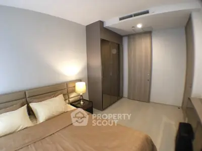 Modern bedroom with stylish decor and cozy lighting, featuring a sleek wardrobe and neutral tones.