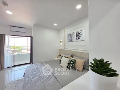 Modern bedroom with stylish decor and balcony view, featuring cozy bedding and elegant wall art.