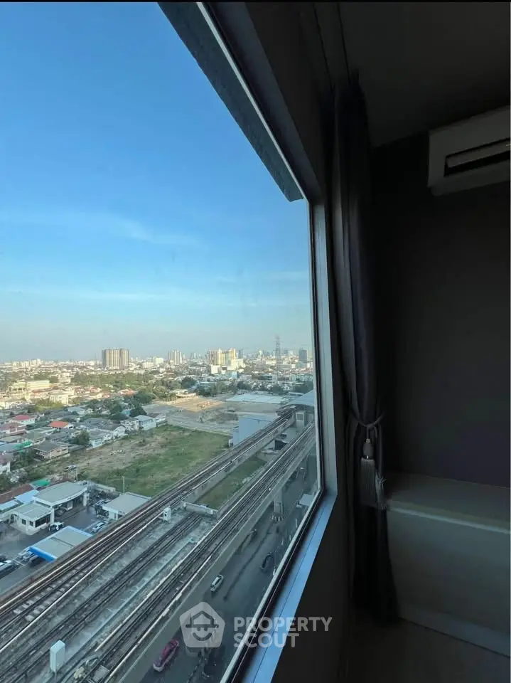 Stunning cityscape view from high-rise apartment window with clear blue sky.
