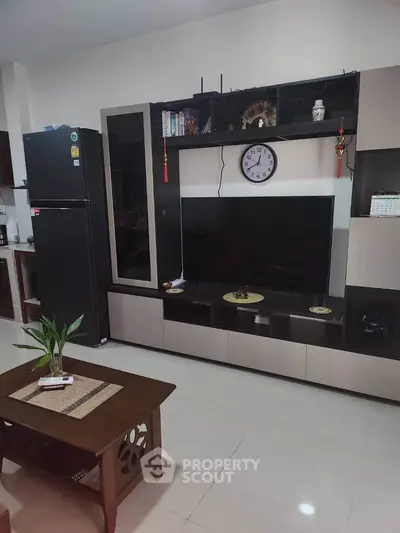 Modern living room with sleek entertainment center and black refrigerator, perfect for contemporary living.