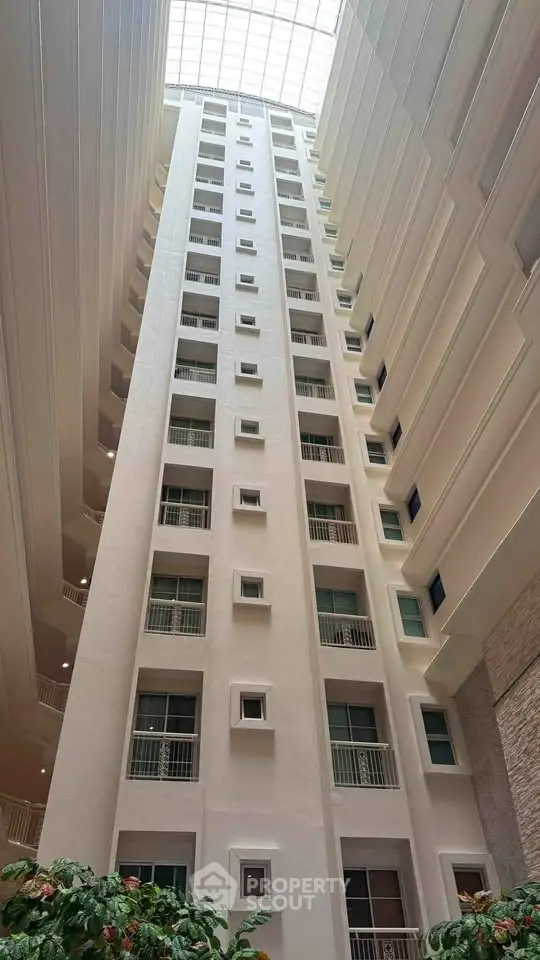 Stunning atrium view of modern high-rise building with natural light and lush greenery.