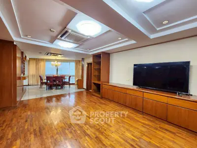 Spacious living room with wooden flooring and large TV, perfect for entertainment.