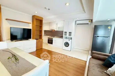 Modern open-layout living room with kitchen, featuring TV, washing machine, and fridge.