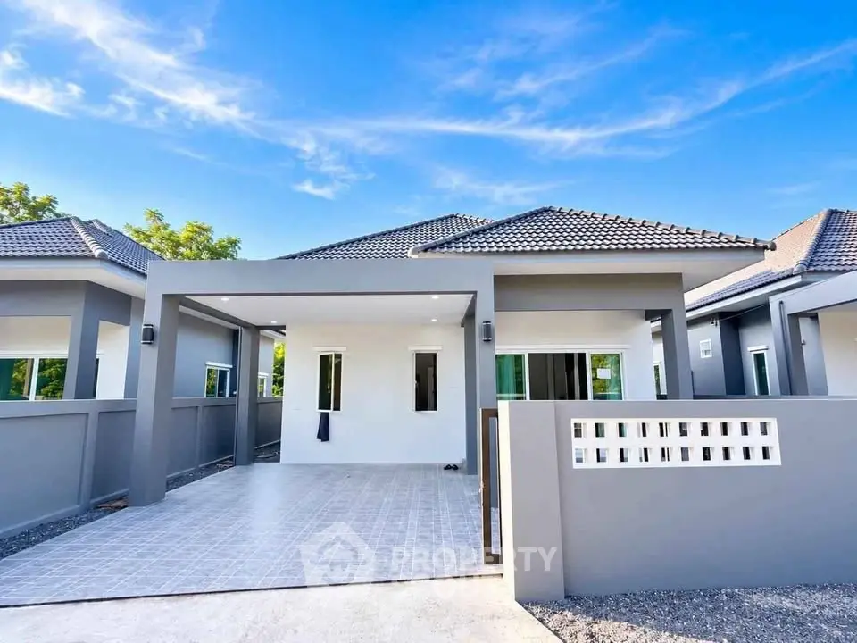 Modern single-story house with sleek gray exterior and spacious driveway under clear blue sky.