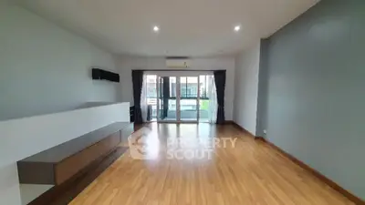 Spacious modern living room with wooden flooring and balcony access
