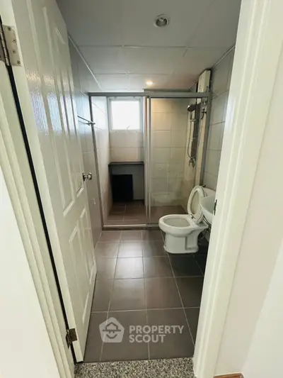 Modern bathroom with glass shower enclosure and tiled flooring in a contemporary apartment.