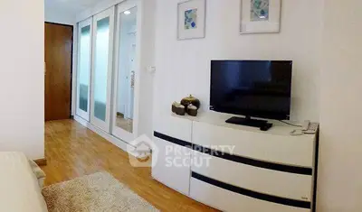 Modern bedroom with sleek wardrobe and TV unit, featuring wooden flooring and stylish decor.