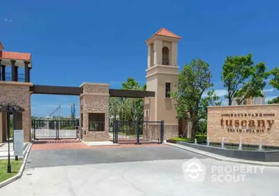 Elegant entrance of Tuscany Boulevard with gated access and lush greenery.