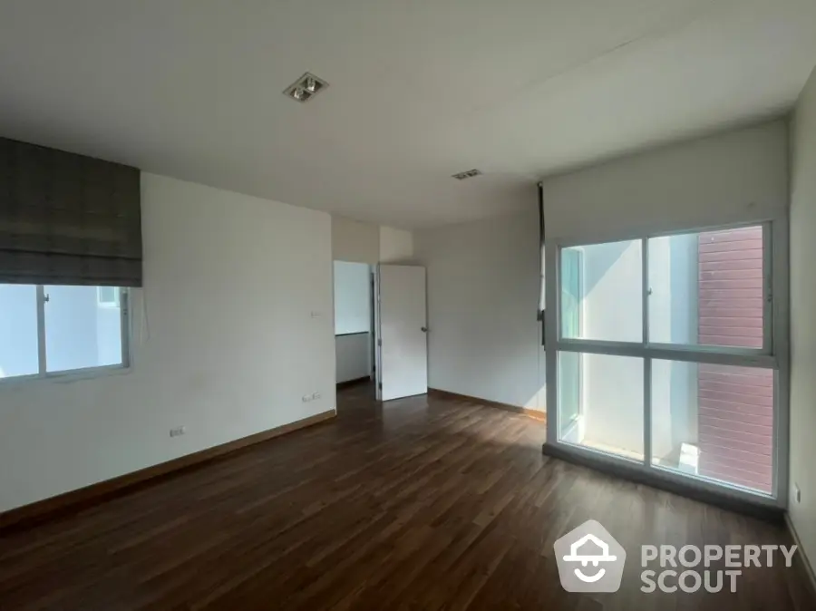 Spacious and well-lit corner unit living room with hardwood flooring and large windows leading to a cozy balcony, perfect for modern living.