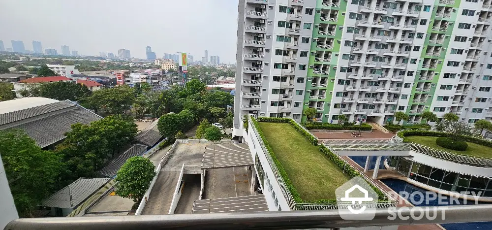 Stunning city view from modern apartment balcony with lush green rooftop garden.