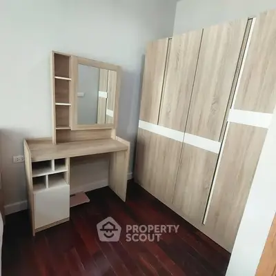 Modern bedroom with wooden wardrobe and vanity on polished hardwood floor.