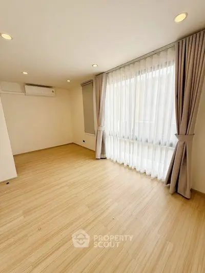 Spacious empty room with large windows and elegant curtains, perfect for customization.