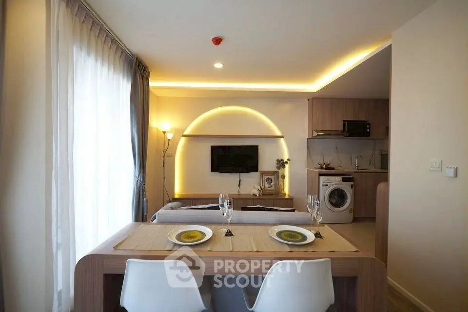 Modern living room with stylish dining area and open kitchen featuring washing machine.