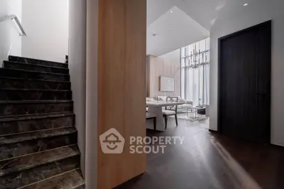 Luxurious modern interior with elegant staircase and spacious living area, featuring high ceilings and stylish decor.