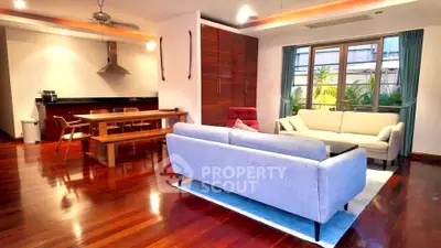 Spacious modern living room with open kitchen, elegant wooden flooring, and stylish furniture.
