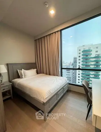 Modern bedroom with city view, large window, and stylish furnishings