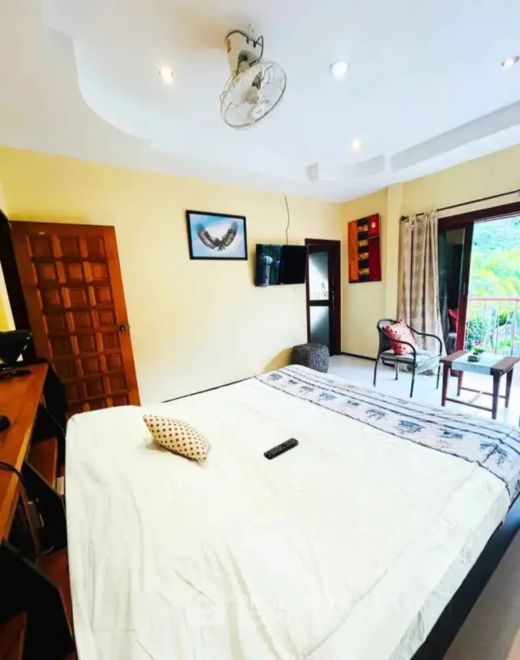 Spacious bedroom with balcony and scenic view, featuring modern decor and natural light.