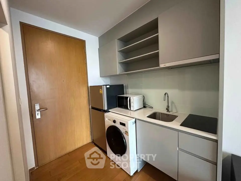 Modern compact kitchen with sleek appliances and ample storage in a stylish apartment.