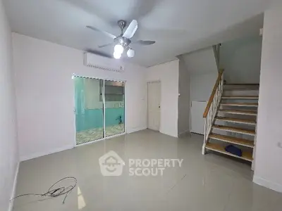 Spacious living room with ceiling fan and staircase in modern home