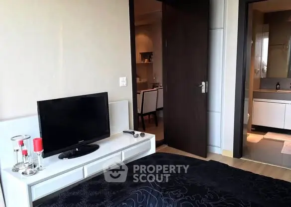 Modern bedroom with TV and view into bathroom, stylish interior design