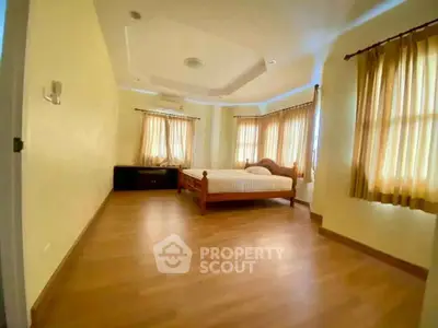 Spacious bedroom with wooden flooring and natural light