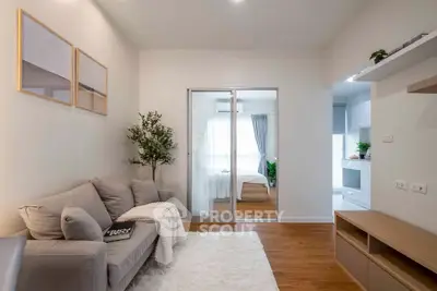 Modern living room with cozy sofa and stylish decor leading to a bright bedroom and kitchen.