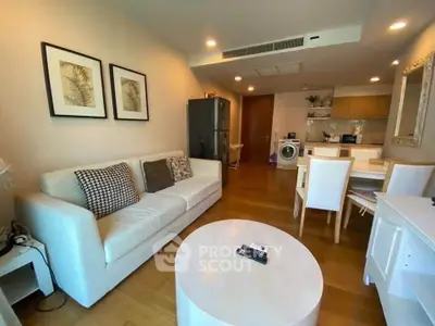 Modern living room with cozy white sofa, dining area, and open kitchen featuring a washing machine.