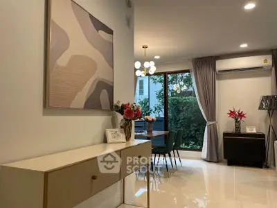 Stylish living room with modern decor and garden view, featuring elegant lighting and chic furniture.