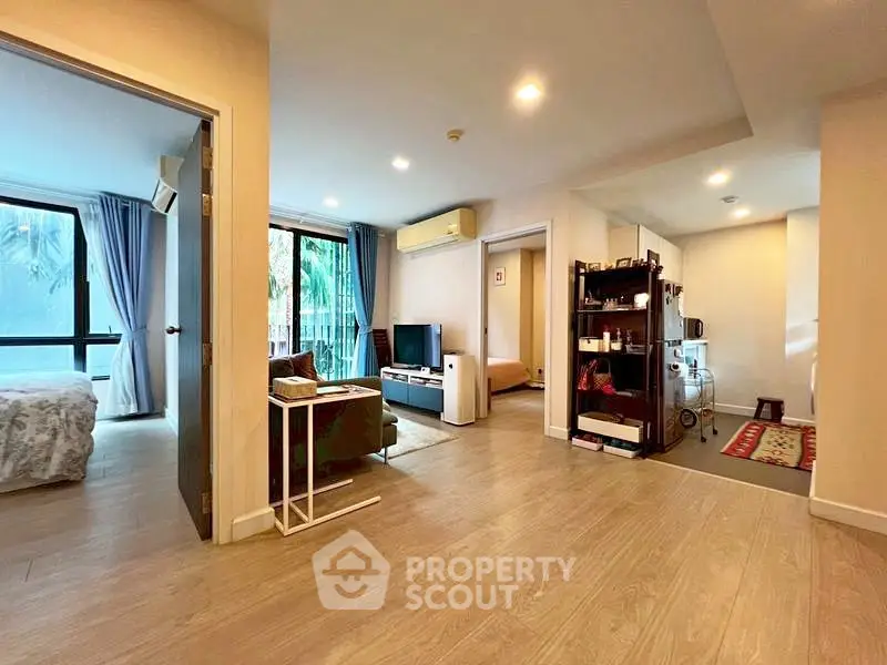 Spacious open-plan living area with modern decor and natural light, featuring a cozy living room and adjacent bedroom.