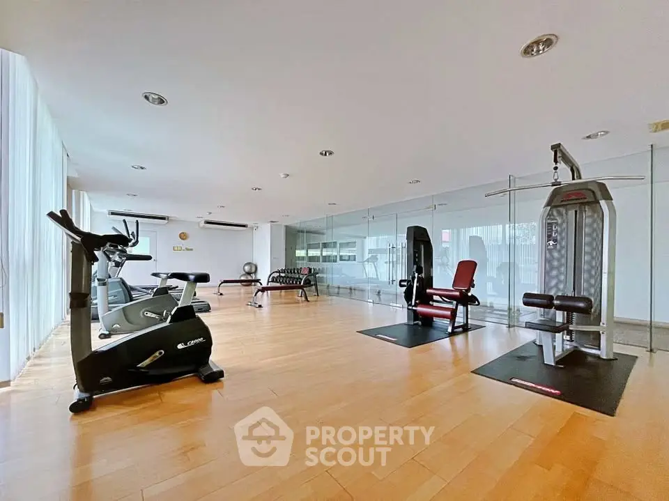 Spacious modern gym with state-of-the-art equipment and wooden flooring in a luxury residential building.