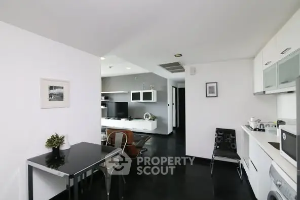Modern open-plan living room and kitchen with sleek black flooring and stylish decor.