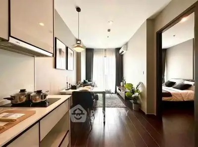 Modern open-plan apartment with sleek kitchen and cozy living area, leading to a stylish bedroom.