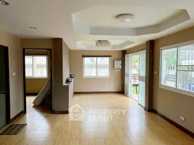Spacious living room with large windows and wooden flooring, perfect for natural light and comfort.