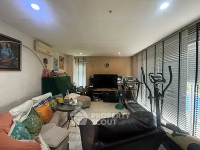 Spacious living room with exercise equipment and cozy seating area, perfect for relaxation and fitness.