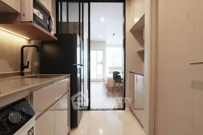 Modern kitchen with sleek appliances and open layout leading to a bright living area.
