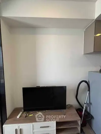 Modern living room with sleek TV setup and vacuum cleaner, showcasing minimalist design and functionality.