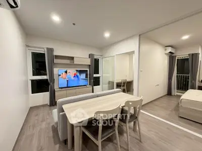Modern open-plan living room with dining area and bedroom, featuring sleek furniture and neutral tones.