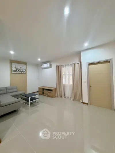 Spacious modern living room with sleek tile flooring and stylish furniture, perfect for relaxation and entertainment.