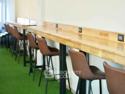 Modern study area with high chairs and wooden desk on green carpet