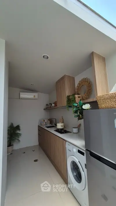 Modern kitchen with sleek cabinetry, washing machine, and fridge in a compact layout.
