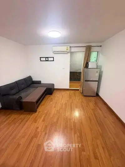 Spacious living room with wooden flooring and modern furniture in a cozy apartment.