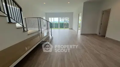 Spacious modern living room with wooden flooring and large windows offering natural light.
