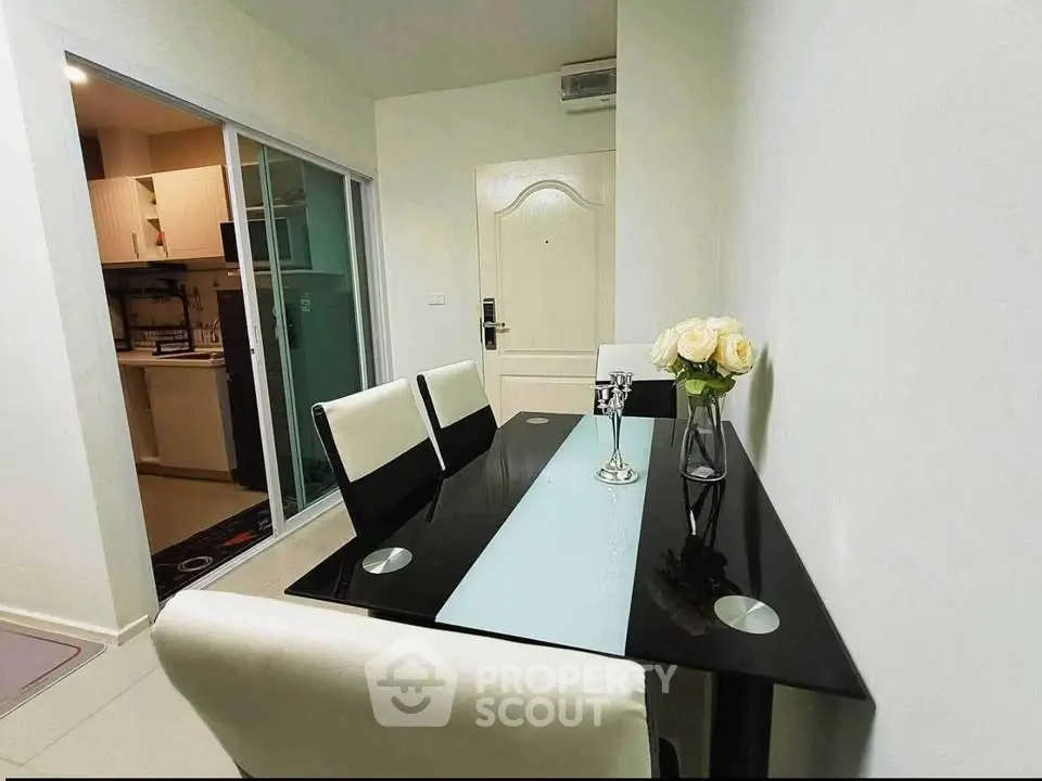 Modern dining area with sleek black table and elegant white chairs in a stylish apartment.