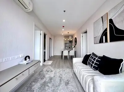 Modern living room with stylish decor and open dining area, featuring elegant furniture and contemporary art.