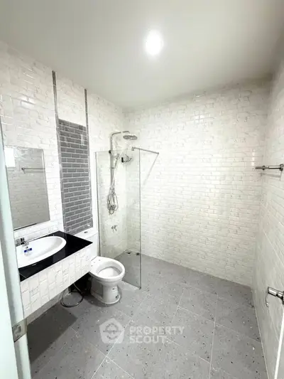 Modern bathroom with sleek design, featuring a glass shower enclosure and stylish tile work.
