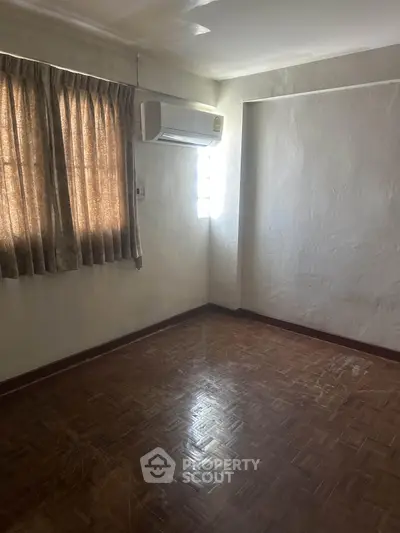Spacious empty room with parquet flooring and air conditioning unit, ideal for customization.