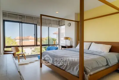 Spacious bedroom with large windows and modern decor, offering a serene view.
